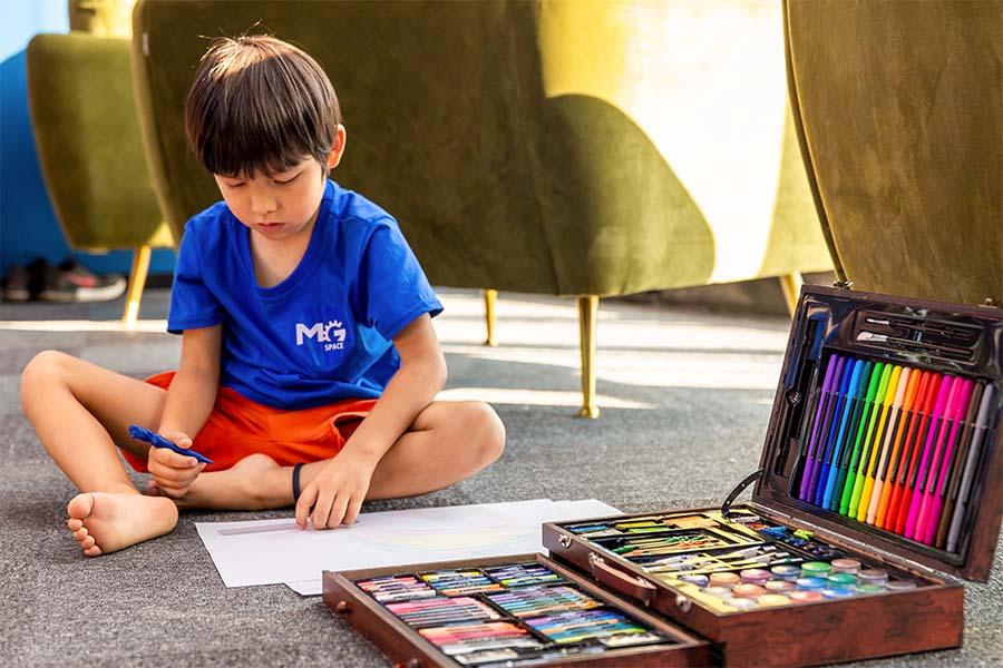 jongetje op grond tekenvel teken- en schilderset in koffer