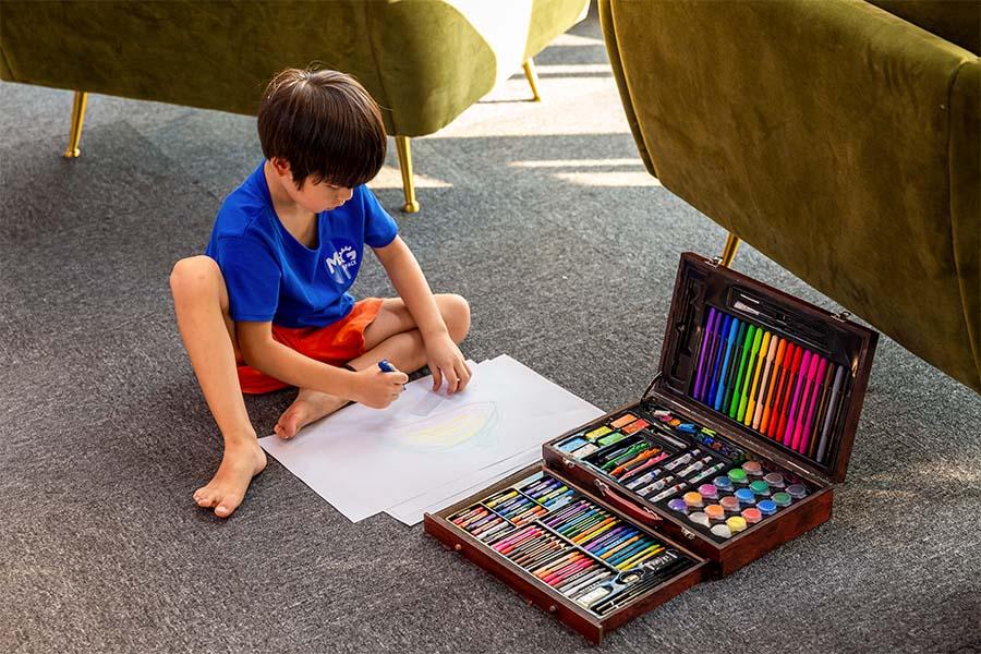 jongetje op grond tekenvel teken- en schilderset in koffer