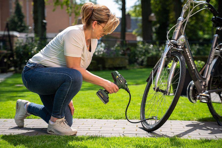 een vrouw die een fietsenband oppompt met een compressor