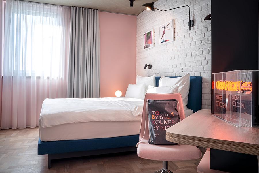 Hotelkamer met bed en roze stoel