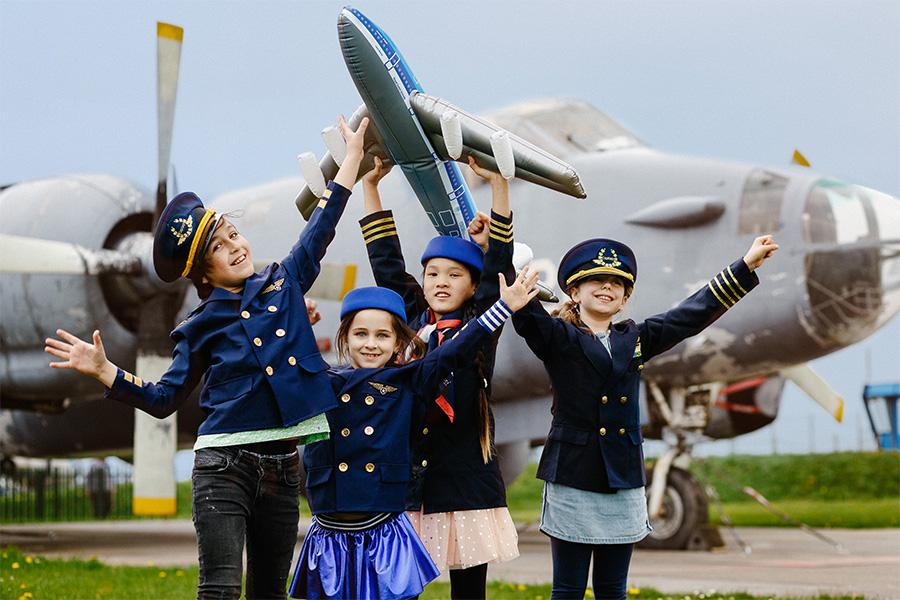 Kinderen in pilotenpak voor een groot vliegtuig op een landingsbaan